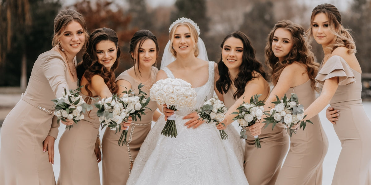 The bride and her bridesmaids pose holding bouquets and looking at the bride. Winter wedding